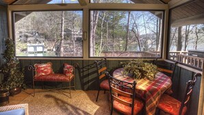 A cozy room with a large window, a ceiling fan, and a table with chairs.