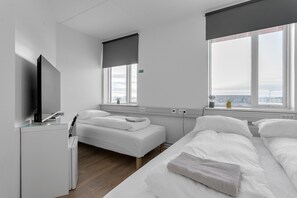 Una habitación de hotel moderna con una cama, un televisor y un ventanal con vistas.