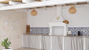 Cozinha com painel decorativo branco e azul, fogão branco e luminárias pendentes.