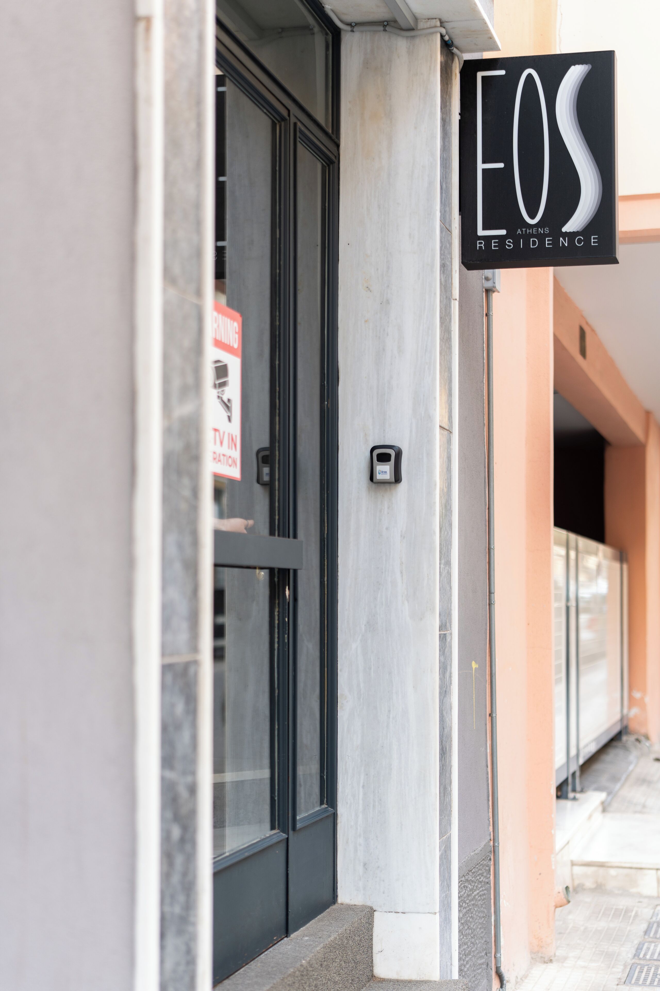 A hotel entrance with a sign reading "EOS ATHENS RESIDENCE".