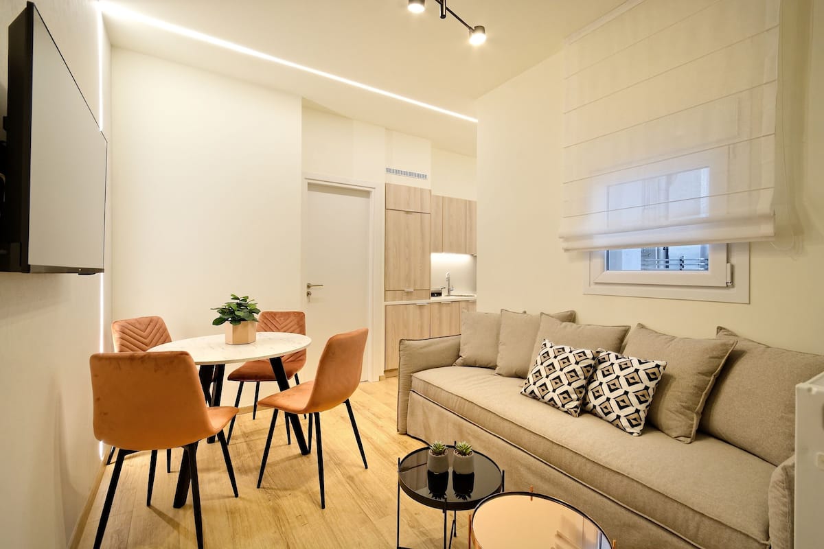 Ein modernes Wohnzimmer mit einer Couch, einem Esstisch mit Stühlen und einem kleinen Couchtisch.