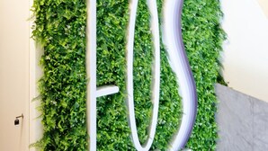 Señal de 'EOS ATHENS RESIDENCE' con un fondo de follaje verde.
