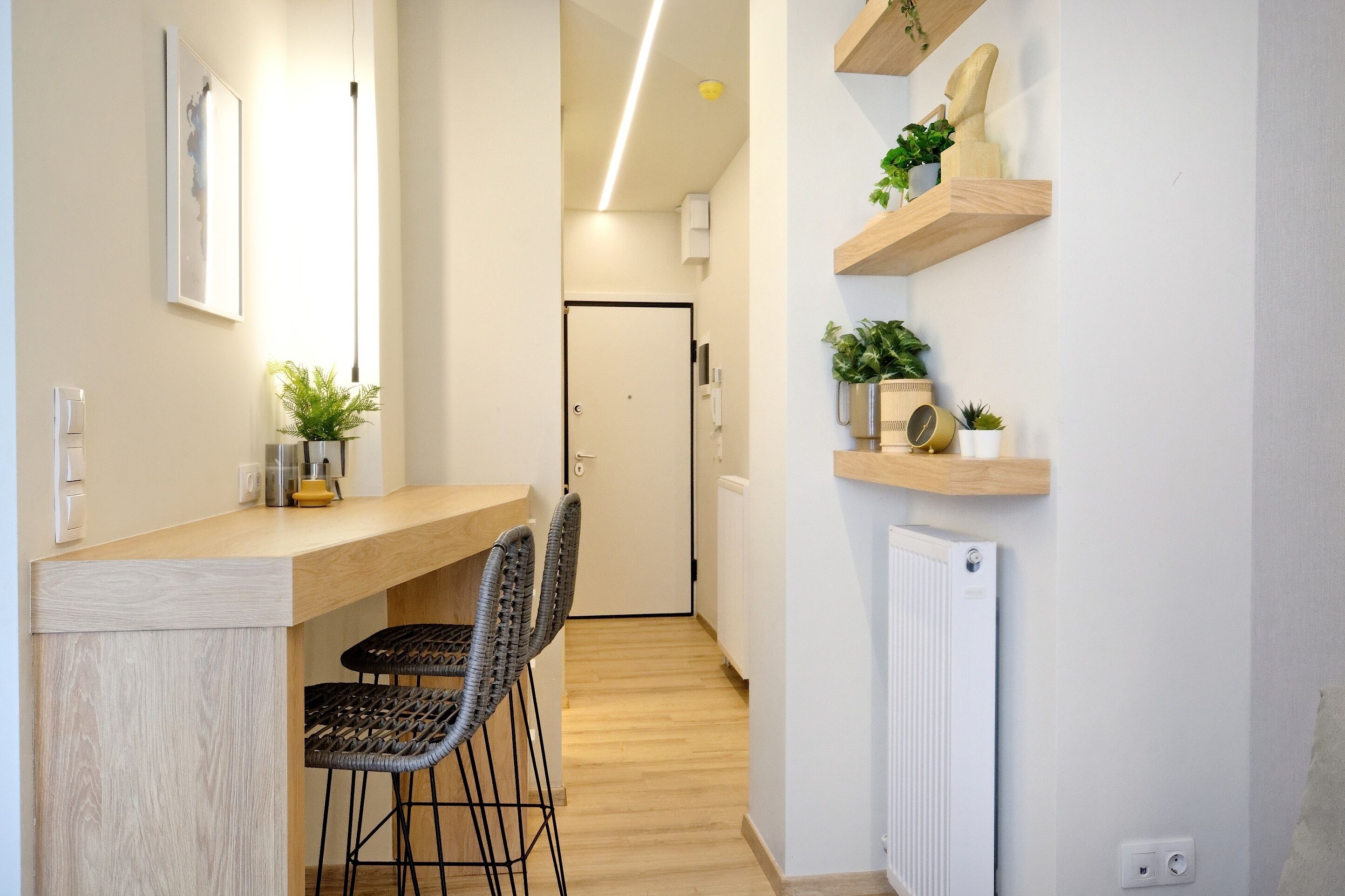A modern kitchen with a wooden countertop, two bar stools, and a white door in the background.