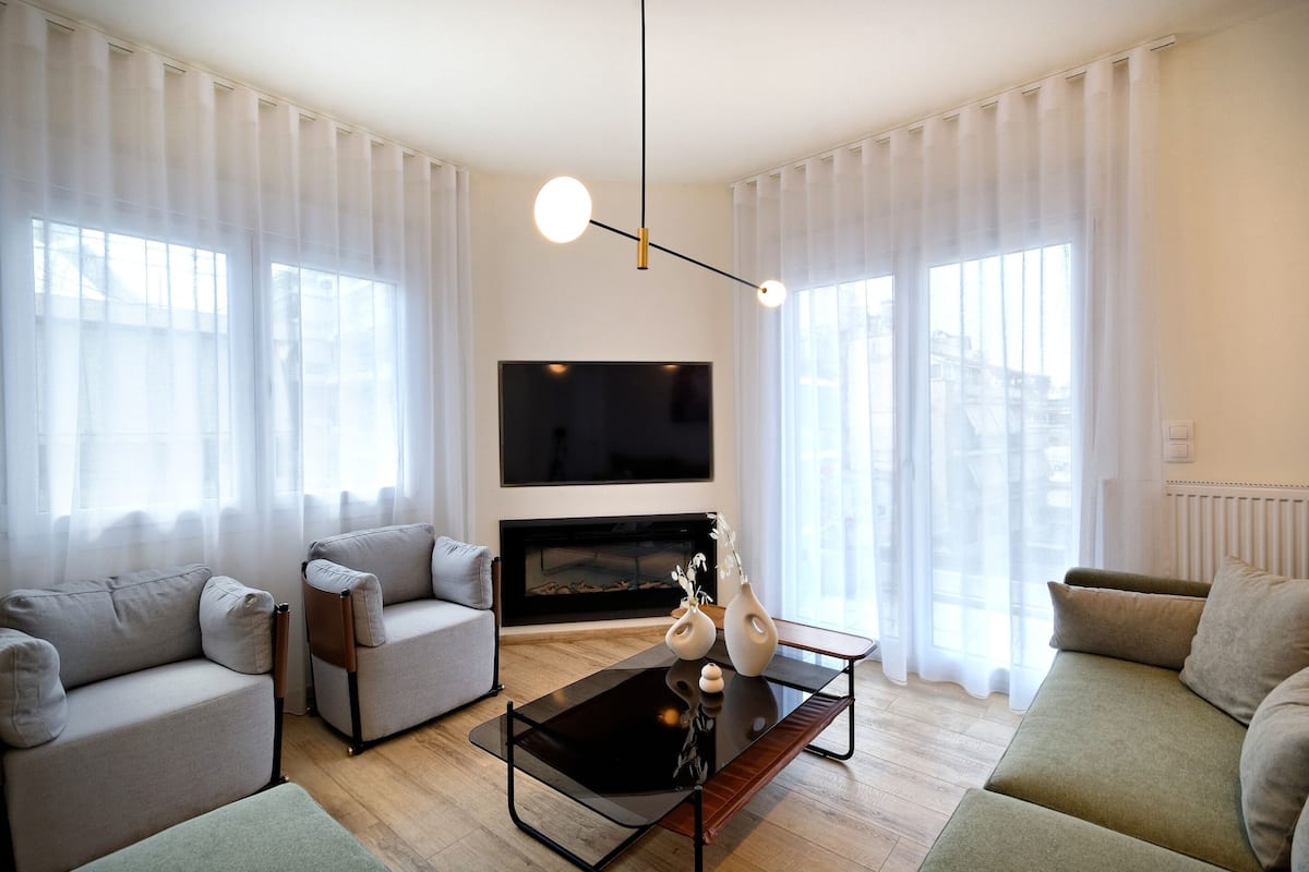 Ein modernes Wohnzimmer mit Flachbildfernseher, zwei Sofas, einem Couchtisch und einem Kamin.