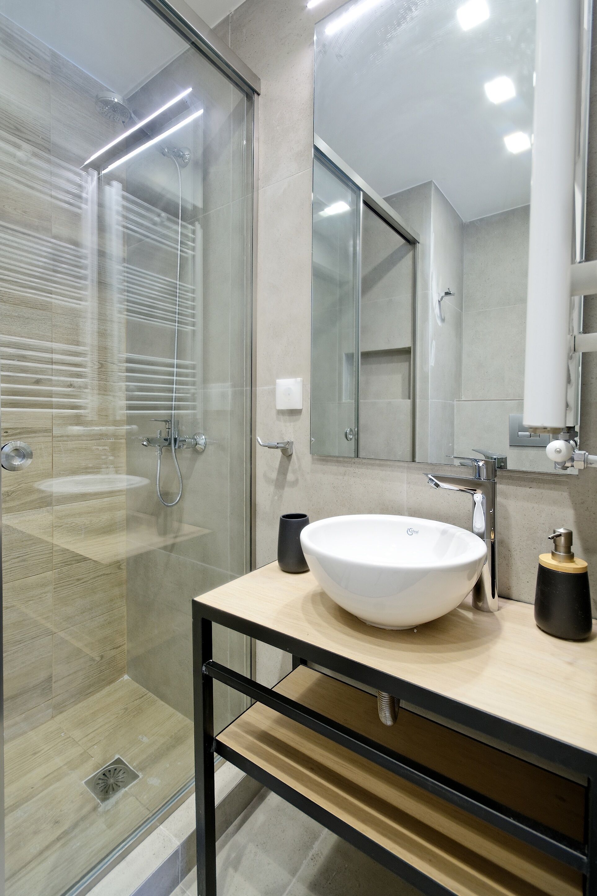 A modern bathroom with a glass-enclosed shower, a large white sink, and a mirror above it.