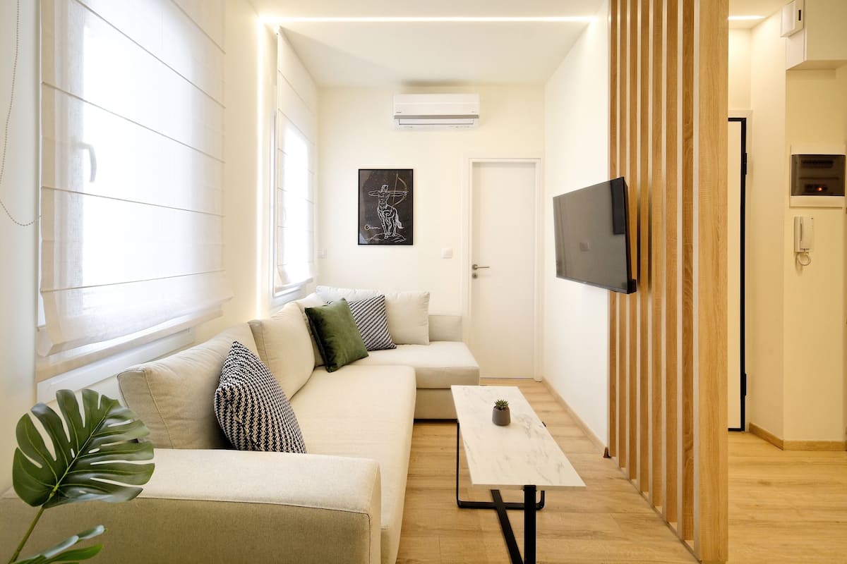 Ein modernes Wohnzimmer mit einer Couch, einem Couchtisch und einem an der Wand montierten Fernseher.