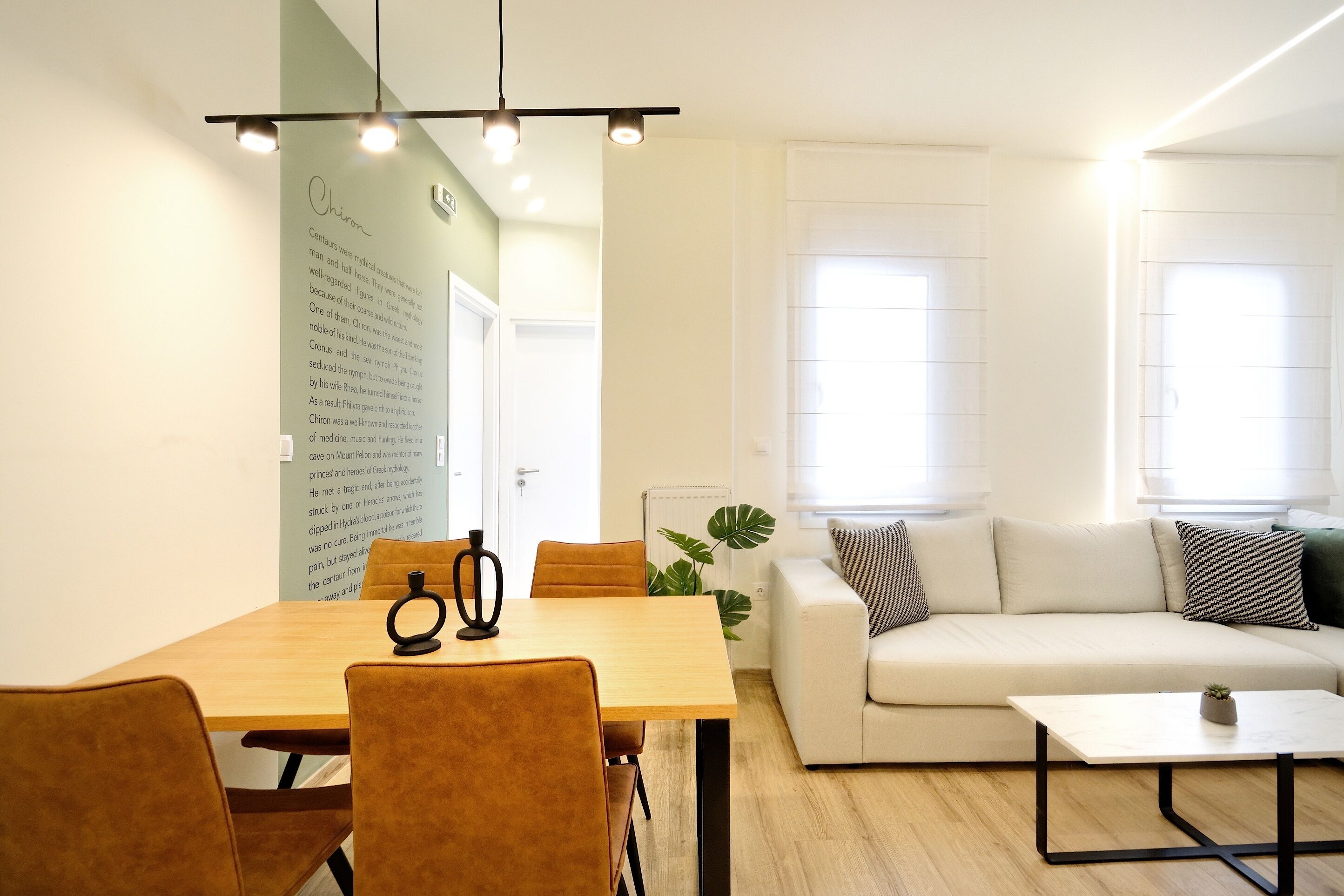 Un salon moderne avec une table à manger en bois, des chaises marron, un canapé blanc et une petite table basse.