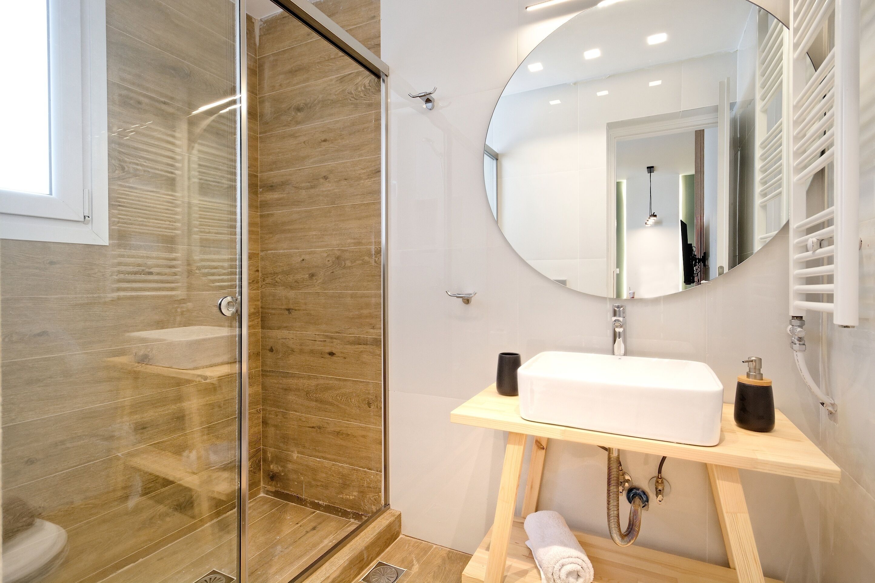 A modern bathroom with a glass shower enclosure, a white sink, and a large mirror.