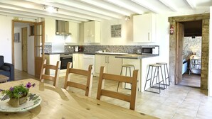 Une cuisine moderne avec des meubles blancs, un îlot central et un coin repas doté de chaises en bois.