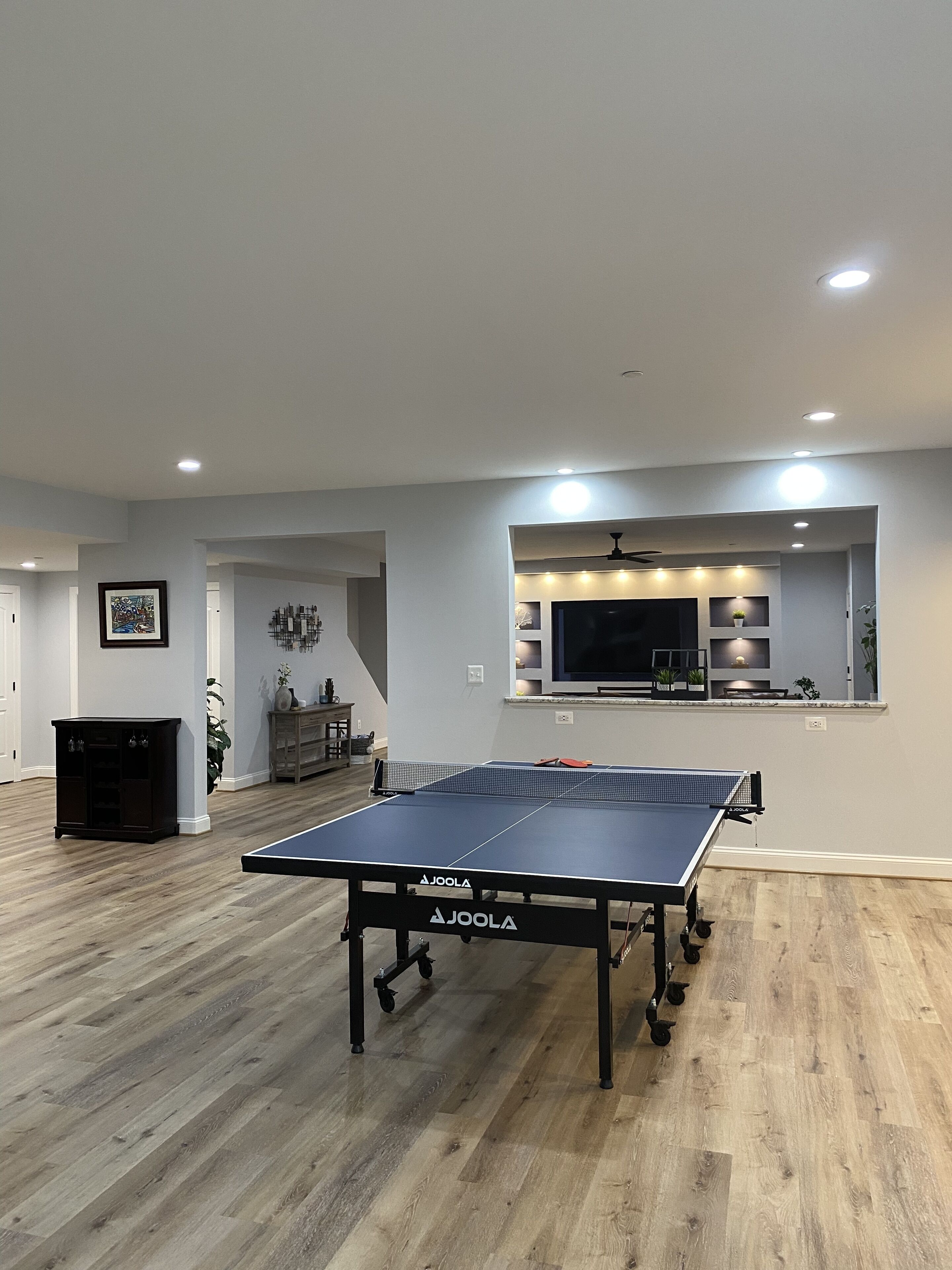 A spacious room with a ping pong table, a TV, and a seating area.