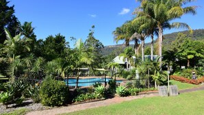 A pool surrounded by lush tropical vegetation, with a clear blue sky and distant hills. - Valley Vista - Three bedroom villa located on golf course with amazing views! (Kangaroo Valley)