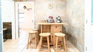 Uma cozinha com uma ilha de madeira, quatro banquetas, um relógio e um ventilador de teto.