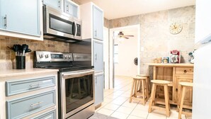 Uma cozinha moderna com eletrodomésticos de aço inoxidável, armários azul-claros e um espaço de bar em madeira.