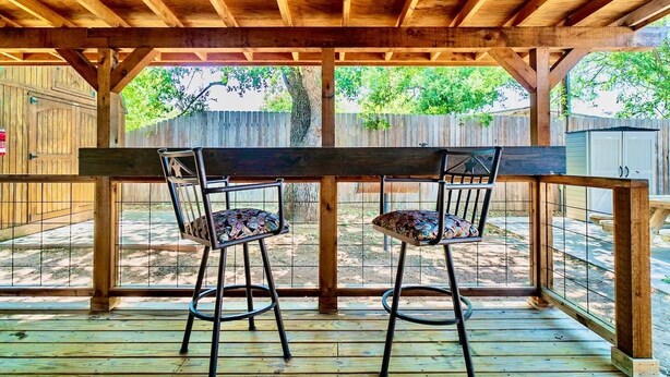 Um deck de madeira com dois bancos altos e uma mesa de madeira.