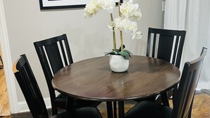 A dining area with a round table, black chairs, a white vase with flowers, and a framed picture on the wall. - 10min from MIZZOU/Univ Hospital/downtown! Family sized, CLEAN! Short term avail! (Columbia)