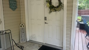 A white door with a wreath, a welcome sign, and a metal bench outside. - 10min from MIZZOU/Univ Hospital/downtown! Family sized, CLEAN! Short term avail! (Columbia)