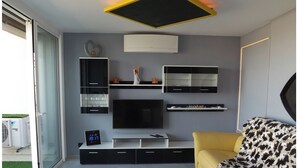En moderne stue med et fladskærms-tv, en sofa og et sofabord.
