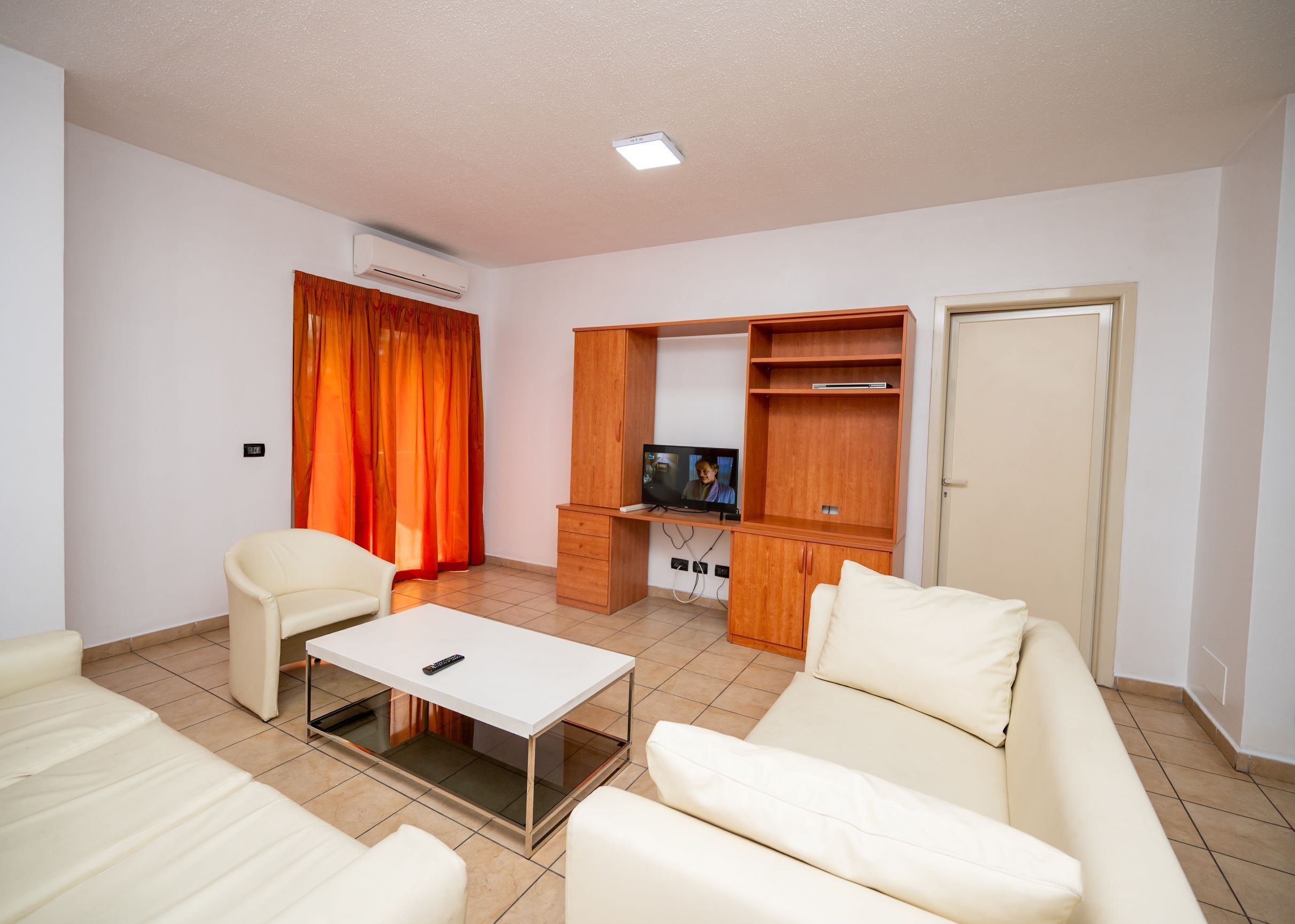 A living room with a sofa, a coffee table, a TV, and a wooden cabinet.