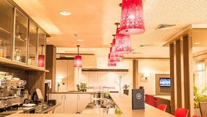 A modern kitchen with a central island, stainless steel appliances, and red pendant lighting.