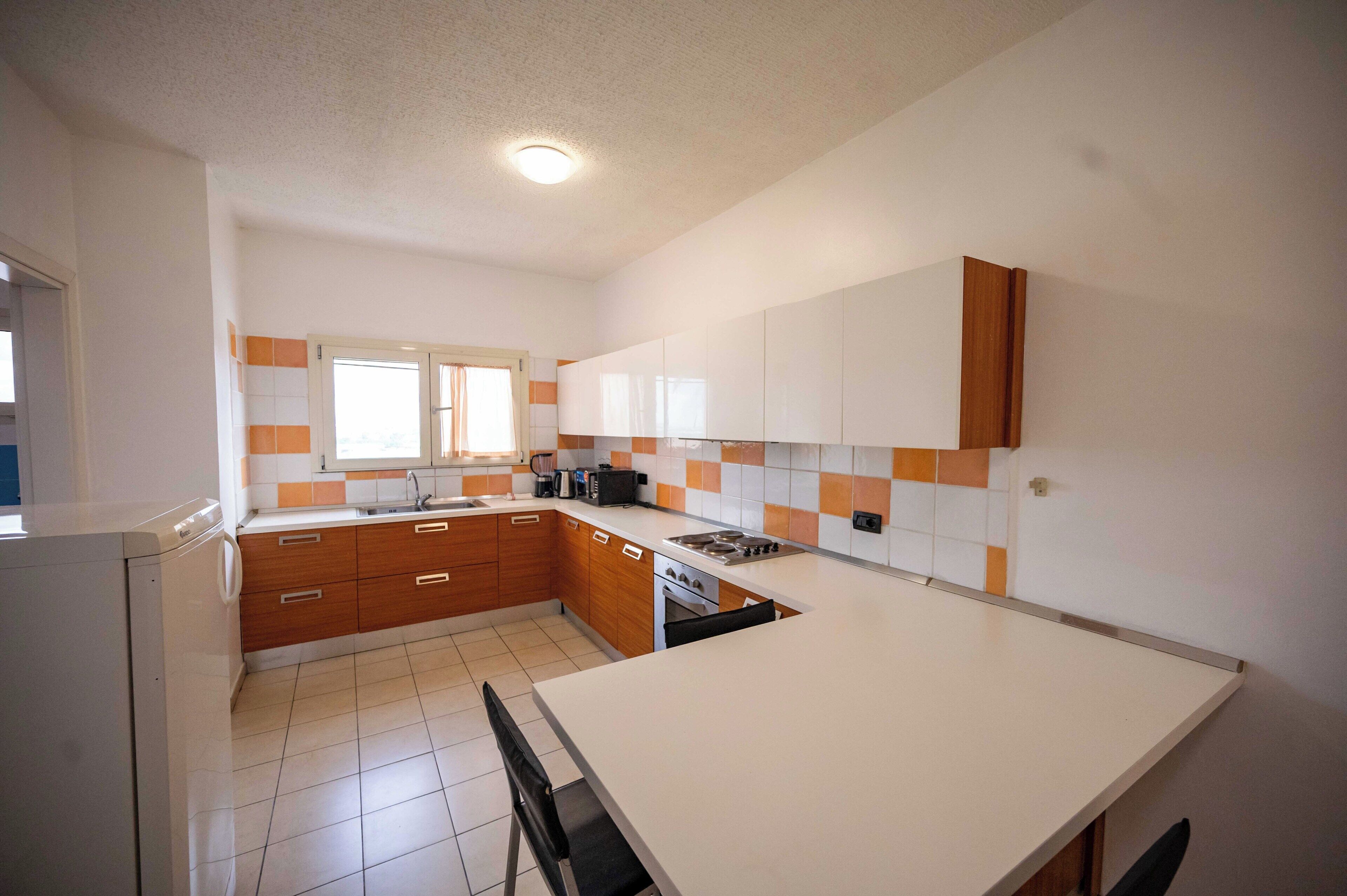 A kitchen with wooden cabinets, a white countertop, and a tiled backsplash.