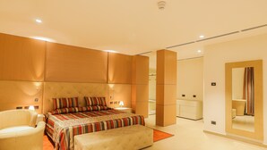 A modern bedroom with a large bed, a sitting area, and a bathroom with a mirror.