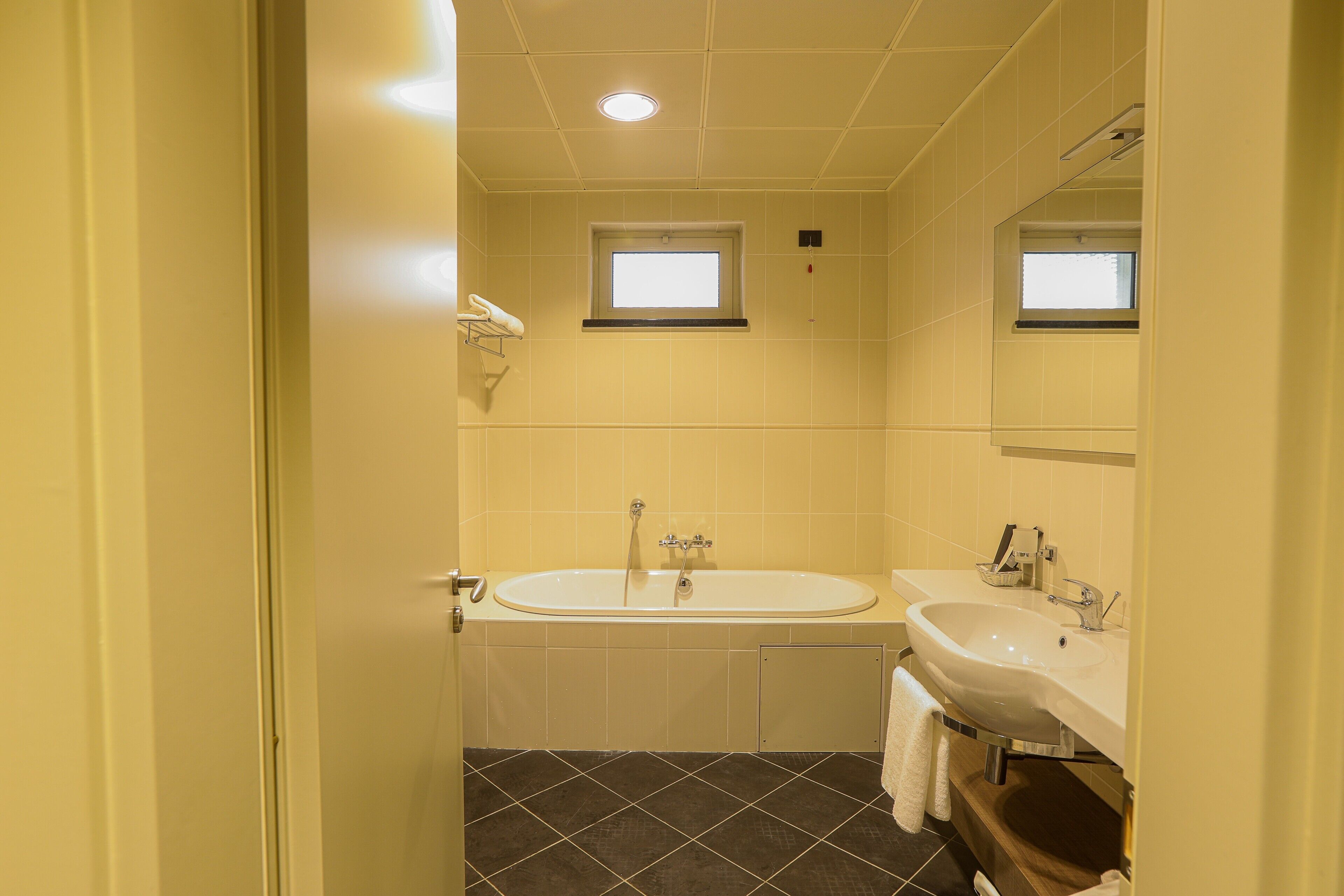 Une salle de bain avec une baignoire, un lavabo et une fenêtre.