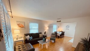 Ein Wohnzimmer mit einer Couch, Couchtisch und einem Essbereich mit Stühlen und Tisch.