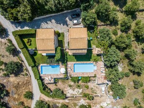 Vue aérienne d’une propriété comprenant deux bâtiments, une piscine et un jardin.