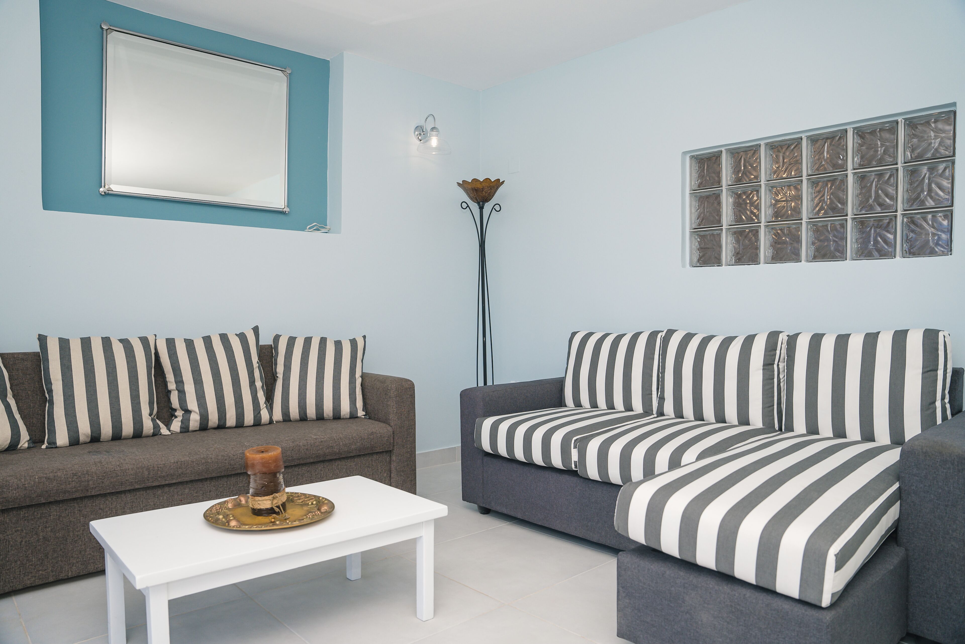 A living room with two sofas, a coffee table, a floor lamp, and a large window with blinds.