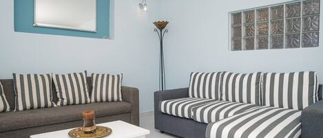A living room with two sofas, a coffee table, a floor lamp, and a large window with blinds.