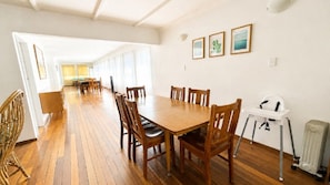 Een ruime eethoek met een lange houten tafel en stoelen, een witte radiator en bewerkte foto's aan de muur.