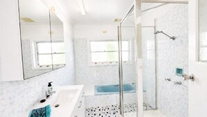 Een moderne badkamer met een douchecabine van glas, een badkuip en een grote spiegel.