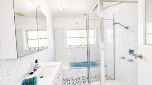 Een moderne badkamer met een douchecabine van glas, een badkuip en een grote spiegel.