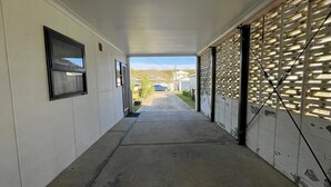 A covered walkway with a garage door, a window, and a door leading to a garage.