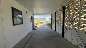 A covered walkway with a garage door, a window, and a door leading to a garage.