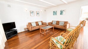 A living room with a sofa set, a coffee table, a television, and a wicker chair.