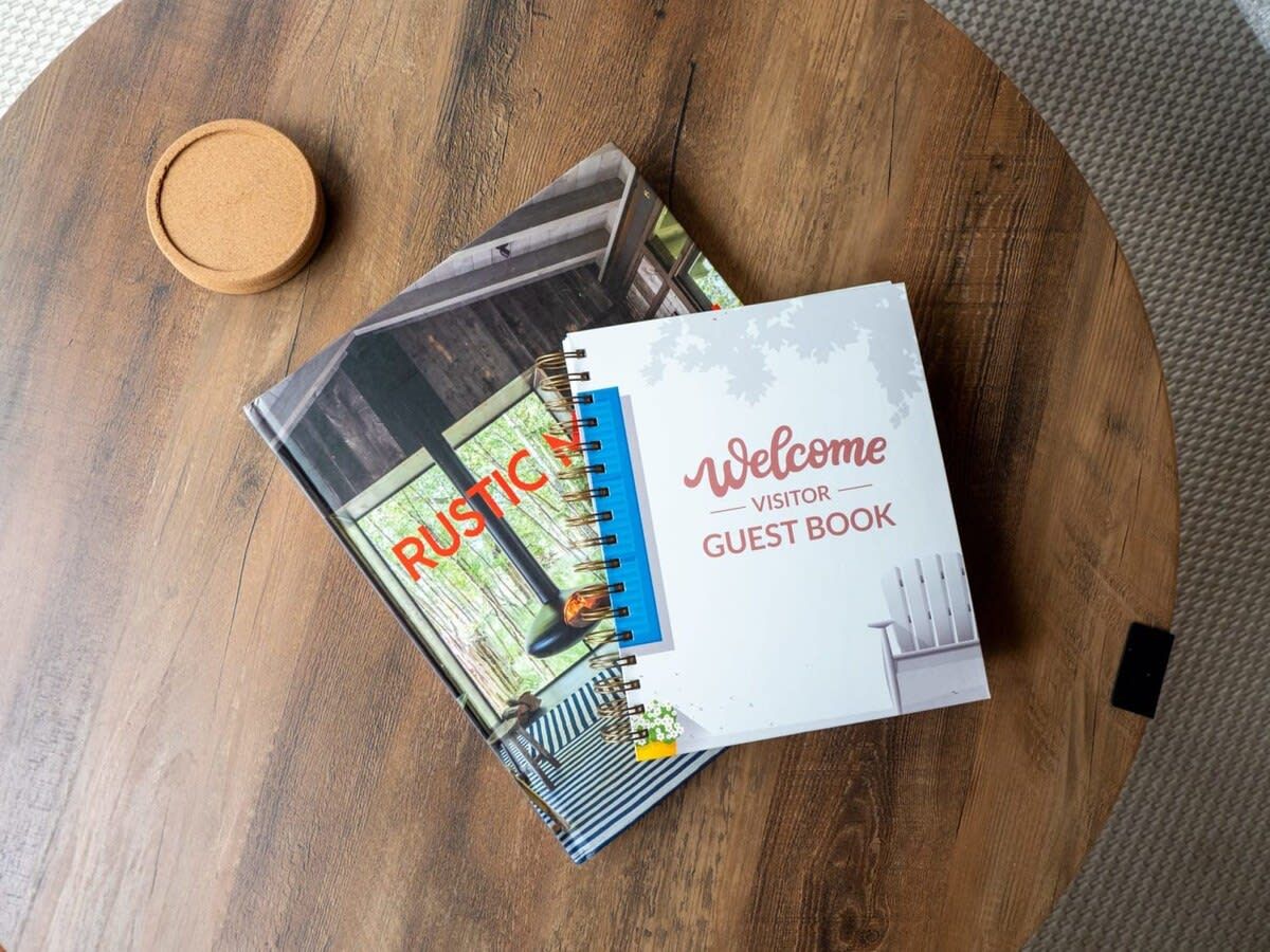 A wooden table with a welcome visitor book and a rustic-themed notebook.