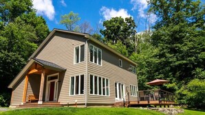 A two-story house with a covered porch and a deck. - Catamount, Zip Line, Private Setting, Book Now! (Egremont)