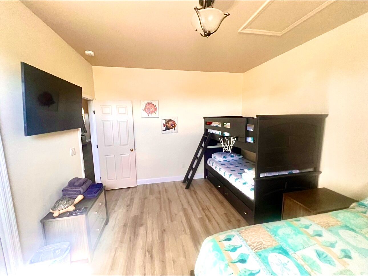 Un dormitorio con literas, un televisor, una puerta y un pequeño escritorio con lámpara.