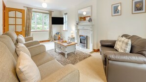 A living room with a fireplace, a sofa, a coffee table, and a television. - 3 bedroom accommodation in Cerrigydrudion (Cerrigydrudion)
