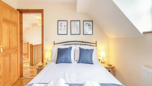 A bedroom with a bed, two bedside lamps, and a wooden door. - 3 bedroom accommodation in Cerrigydrudion (Cerrigydrudion)