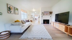 A living room with a white sofa, a large TV, and a fireplace. - Boho Beach Villa- minutes to the ocean  (Vero Beach)