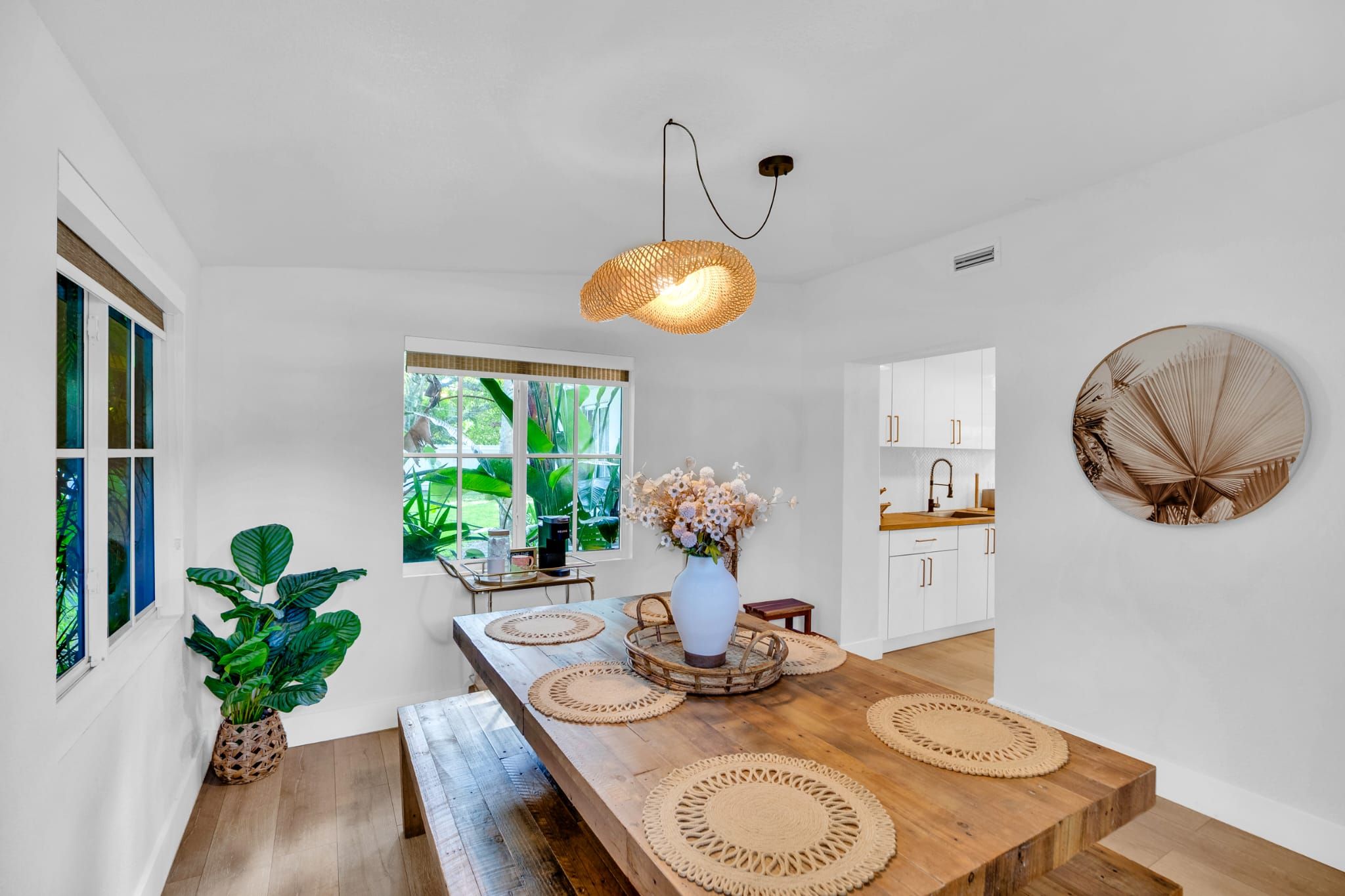 A modern kitchen with white cabinets, a wooden countertop, and a hanging light fixture.