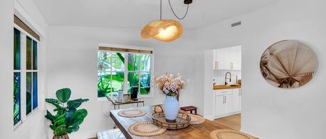 A modern kitchen with white cabinets, a wooden countertop, and a hanging light fixture.