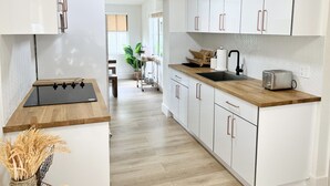 A modern kitchen with white cabinets, a wooden countertop, and a black faucet. - Boho Beach Villa- minutes to the ocean  (Vero Beach)