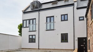A modern two-story building with multiple windows, a flat roof with solar panels, and a small balcony. - Belford House @ Seahouses (Seahouses)
