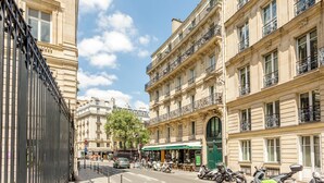 Une vue de rue avec des immeubles, un auvent vert et des scooters garés.