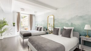 Une chambre d’hôtel moderne avec deux lits, un grand miroir et une vue sur l’extérieur.