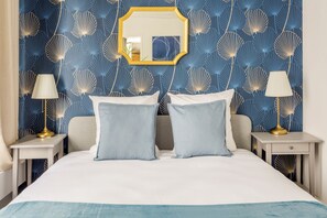 A bedroom with a bed, two bedside tables, two lamps, and a mirror on the wall. - Merveil - Family suite - Louvre - Victoires (Paris)