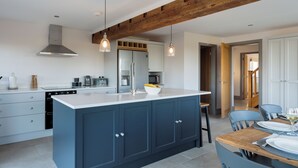 A modern kitchen with a central island, built-in appliances, and pendant lighting. - The Maddocks - UK36311 (Whitchurch)